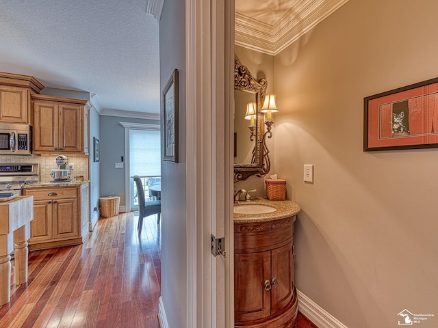 bathroom featuring hardwood / wood-style floors, tasteful backsplash, ornamental molding, vanity, and a textured ceiling