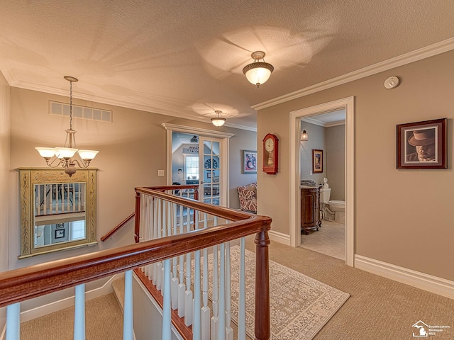 corridor featuring crown molding, light colored carpet, a chandelier, and a textured ceiling