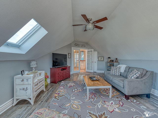 living room featuring hardwood / wood-style floors, lofted ceiling with skylight, a textured ceiling, and ceiling fan