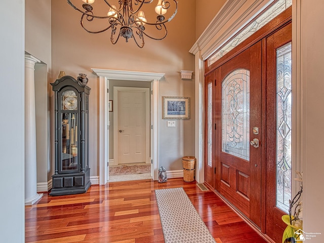 entrance foyer featuring a chandelier, decorative columns, hardwood / wood-style floors, and a high ceiling