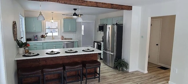 kitchen with sink, appliances with stainless steel finishes, hanging light fixtures, light hardwood / wood-style floors, and a kitchen bar