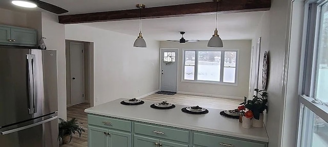 kitchen with hanging light fixtures, stainless steel fridge, beamed ceiling, ceiling fan, and light hardwood / wood-style floors