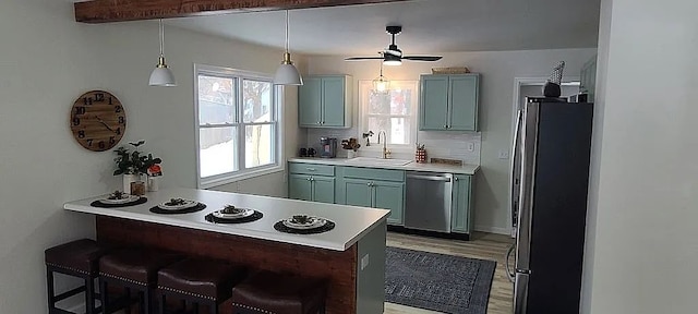 kitchen featuring appliances with stainless steel finishes, a breakfast bar, pendant lighting, sink, and kitchen peninsula