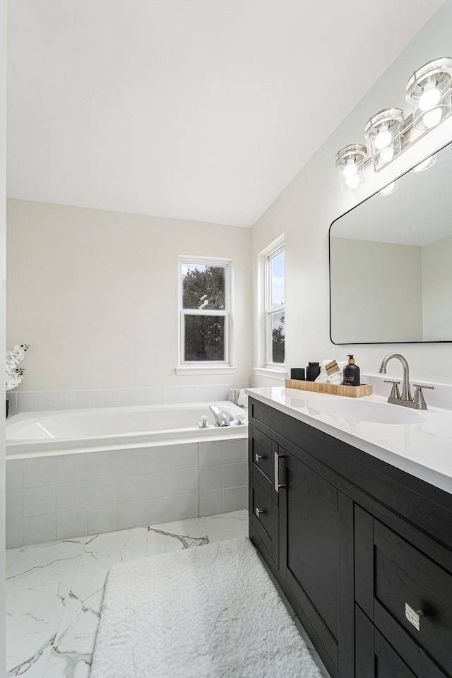 bathroom featuring tiled tub and vanity