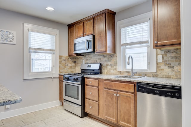 kitchen featuring light stone counters, stainless steel appliances, sink, and plenty of natural light