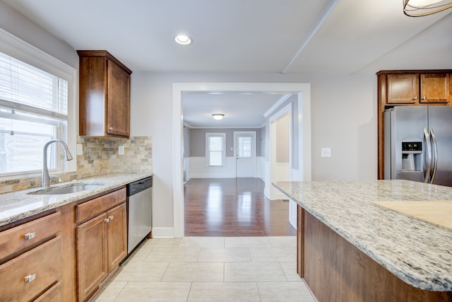 kitchen with tasteful backsplash, sink, stainless steel appliances, and light stone countertops