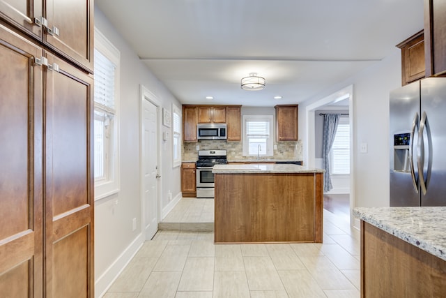 kitchen featuring sink, light stone counters, light tile patterned floors, appliances with stainless steel finishes, and decorative backsplash