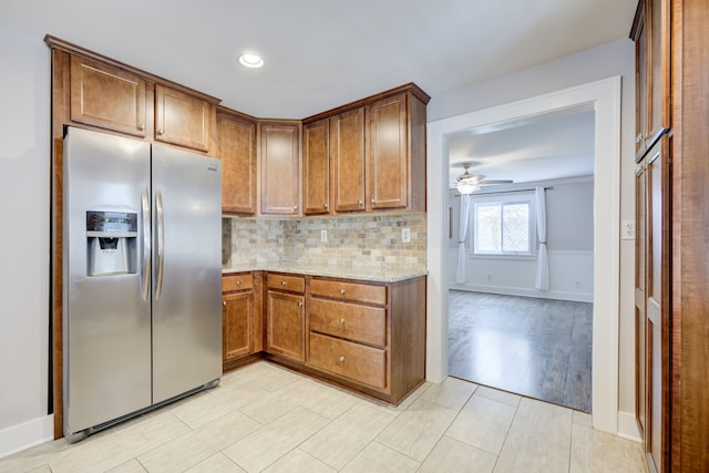 kitchen with light hardwood / wood-style flooring, stainless steel fridge, ceiling fan, light stone countertops, and decorative backsplash