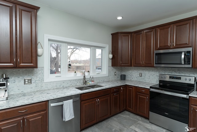 kitchen with stainless steel appliances, sink, backsplash, and light stone counters