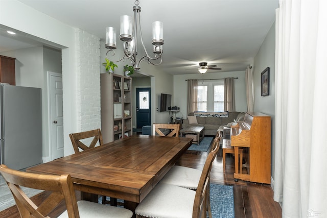 dining area featuring dark wood-type flooring and ceiling fan with notable chandelier