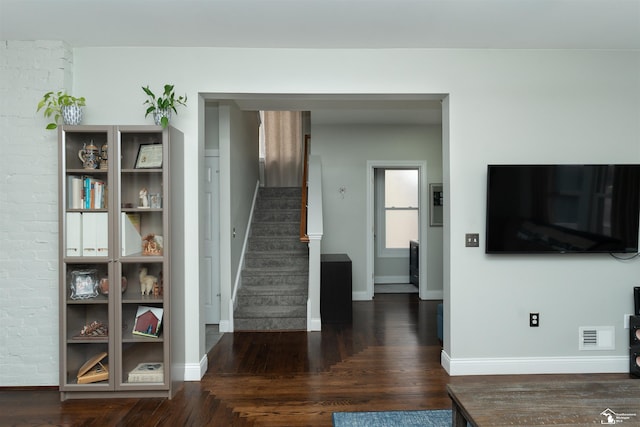 stairway with brick wall and hardwood / wood-style floors