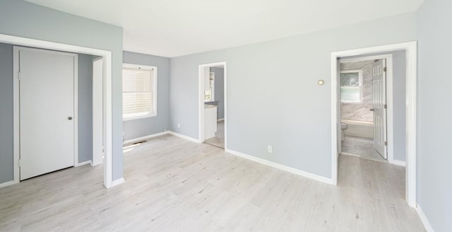 unfurnished bedroom with ensuite bathroom, light hardwood / wood-style floors, and a closet