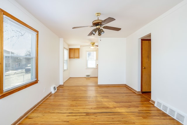 unfurnished living room with crown molding, a wealth of natural light, and light wood-type flooring