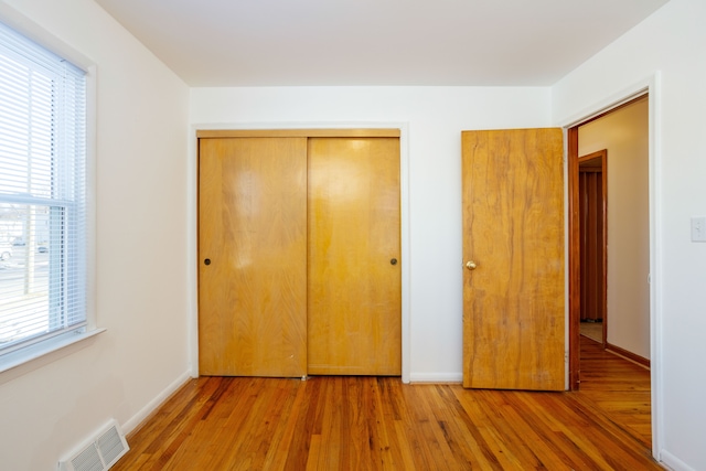 unfurnished bedroom with wood-type flooring and a closet