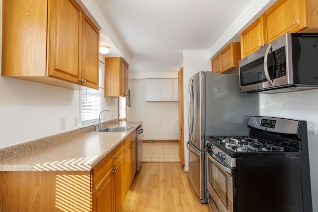 kitchen featuring stainless steel appliances, sink, and light hardwood / wood-style flooring