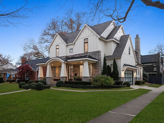 view of front of home featuring covered porch, stone siding, a front lawn, and board and batten siding