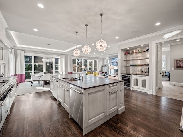 kitchen with beverage cooler, an island with sink, a sink, hanging light fixtures, and stainless steel dishwasher