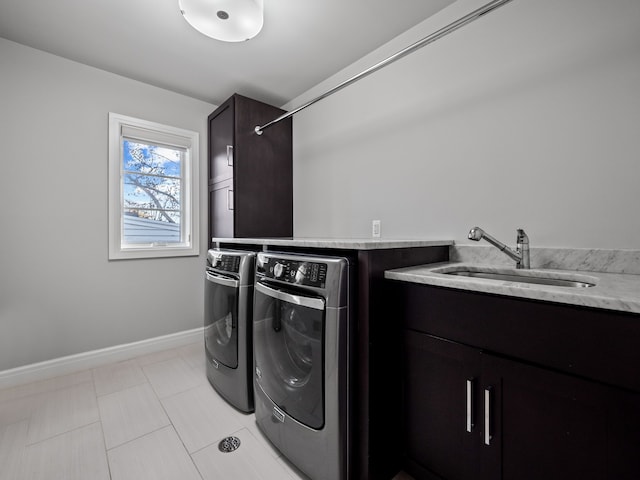 laundry area with cabinet space, washing machine and dryer, baseboards, and a sink