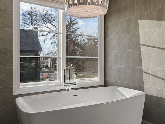 bathroom featuring a freestanding tub, a sink, and tile walls