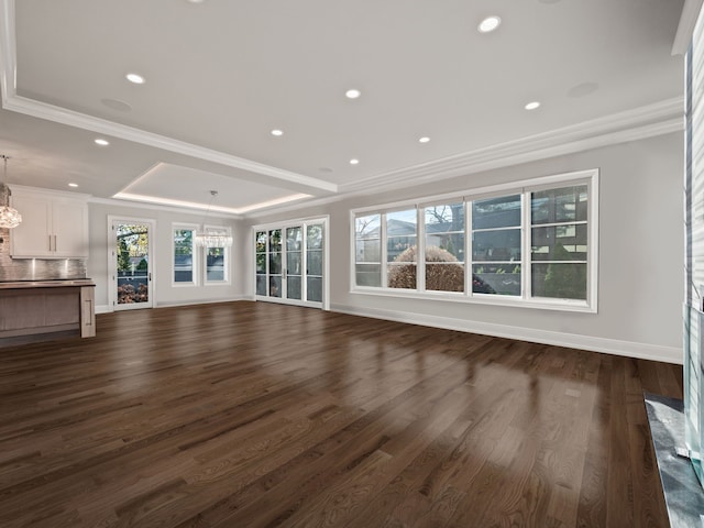 unfurnished living room featuring a tray ceiling, a chandelier, and dark wood-type flooring