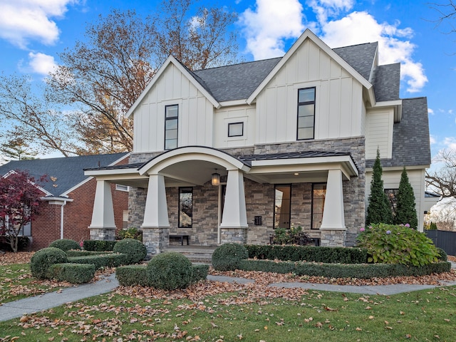 view of front of property with a front yard, a porch, board and batten siding, and roof with shingles