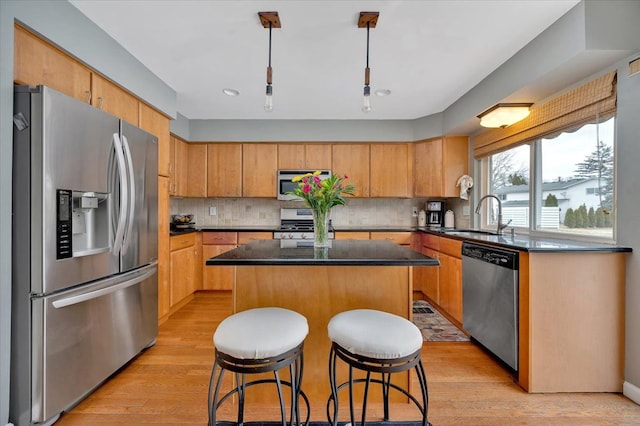 kitchen featuring sink, appliances with stainless steel finishes, a center island, decorative backsplash, and light wood-type flooring