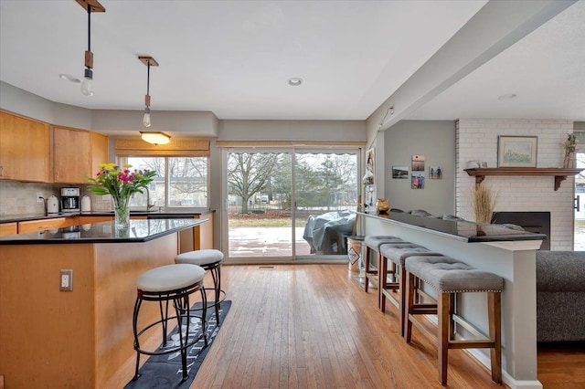 kitchen with a wealth of natural light, decorative light fixtures, a breakfast bar, and light wood-type flooring