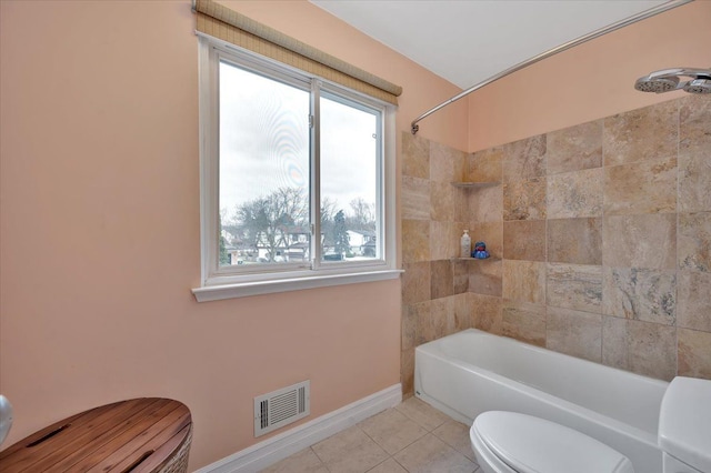 bathroom featuring tiled shower / bath, toilet, and tile patterned flooring