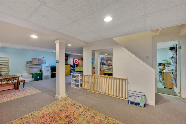 basement featuring a paneled ceiling and carpet flooring