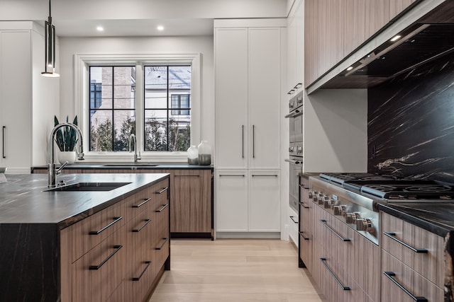 kitchen featuring pendant lighting, sink, backsplash, and stainless steel gas cooktop