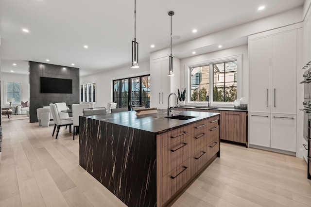 kitchen featuring pendant lighting, sink, a center island with sink, and light hardwood / wood-style floors