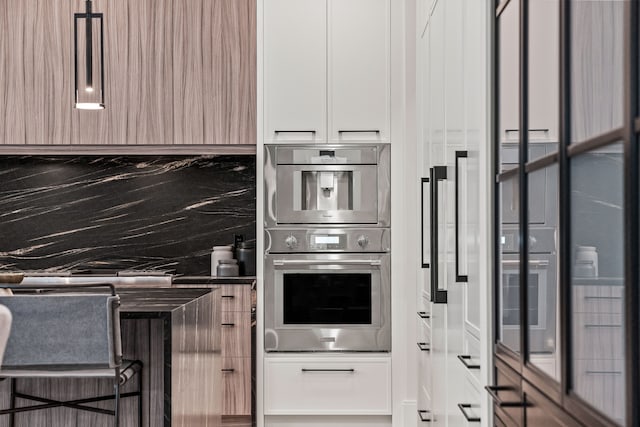 kitchen with tasteful backsplash, stainless steel double oven, and white cabinets