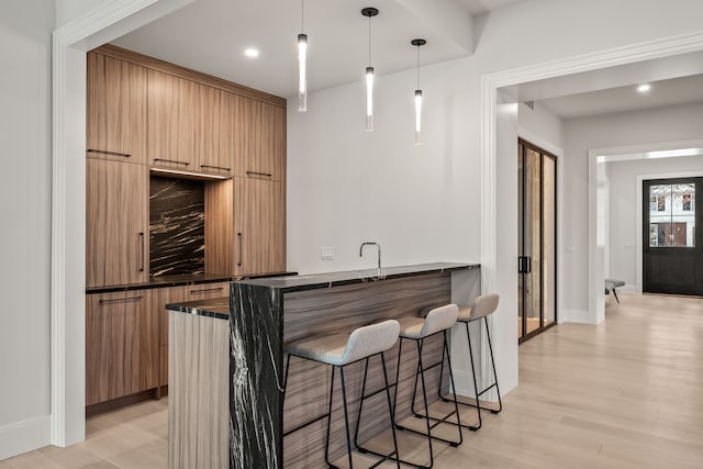 bar with pendant lighting and light hardwood / wood-style flooring