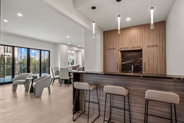 bar featuring hanging light fixtures, french doors, and light wood-type flooring