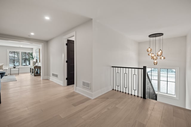 hall with a chandelier and light wood-type flooring