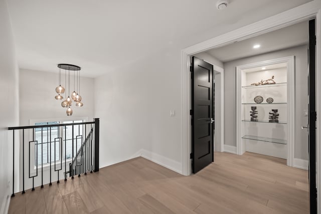 hall with an inviting chandelier and light wood-type flooring