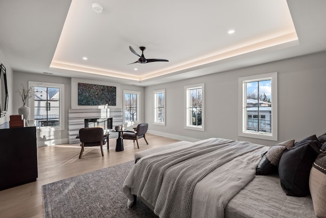 bedroom with multiple windows, a raised ceiling, and light hardwood / wood-style flooring