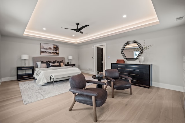 bedroom featuring light hardwood / wood-style floors, a raised ceiling, and ceiling fan