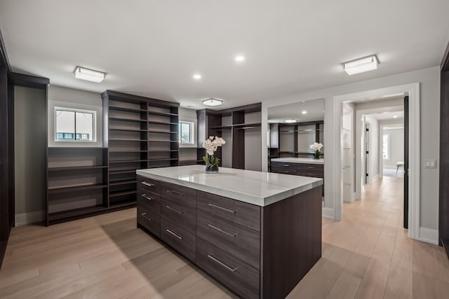 kitchen with light stone countertops, a center island, light hardwood / wood-style floors, and dark brown cabinets