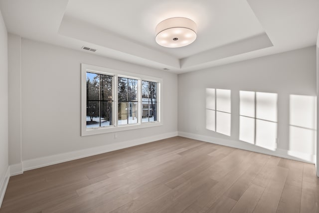 unfurnished room featuring a tray ceiling and hardwood / wood-style floors