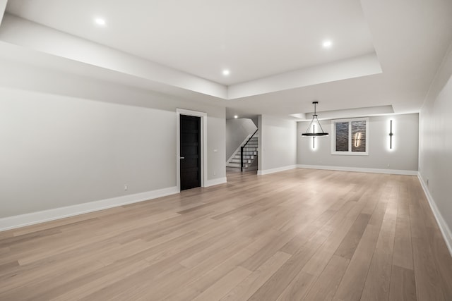 unfurnished living room with a tray ceiling and light hardwood / wood-style floors