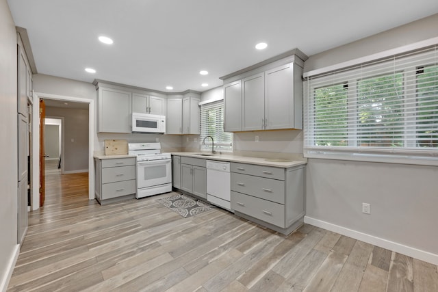 kitchen with white appliances, sink, light hardwood / wood-style floors, and gray cabinetry