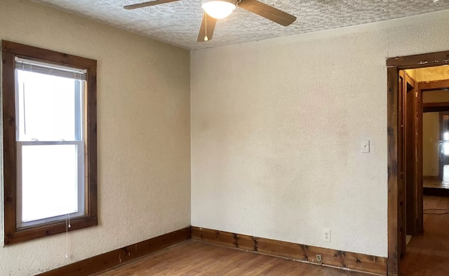 spare room featuring ceiling fan, wood-type flooring, a textured ceiling, and a wealth of natural light