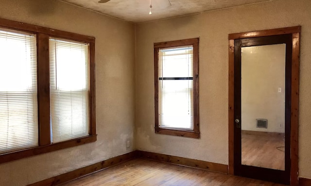 spare room featuring ceiling fan, a healthy amount of sunlight, and hardwood / wood-style floors