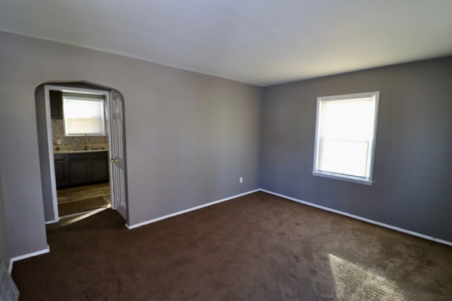 unfurnished room featuring sink and dark carpet