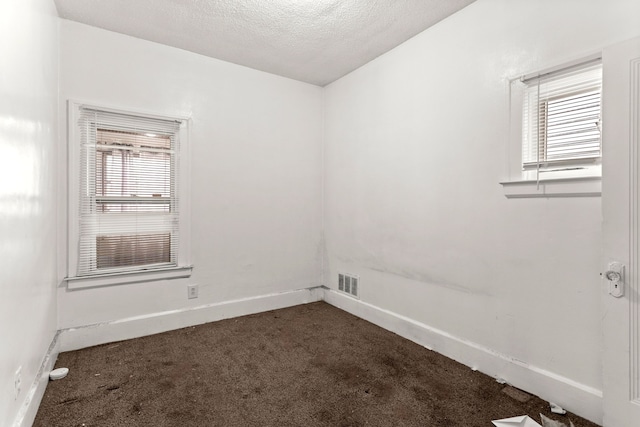 carpeted empty room with a textured ceiling