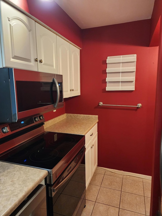 kitchen featuring stainless steel appliances, light tile patterned floors, and white cabinets