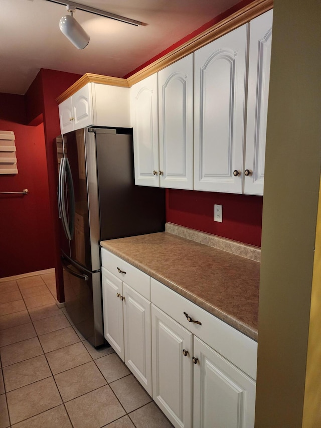 kitchen with white cabinetry, stainless steel fridge, and light tile patterned flooring