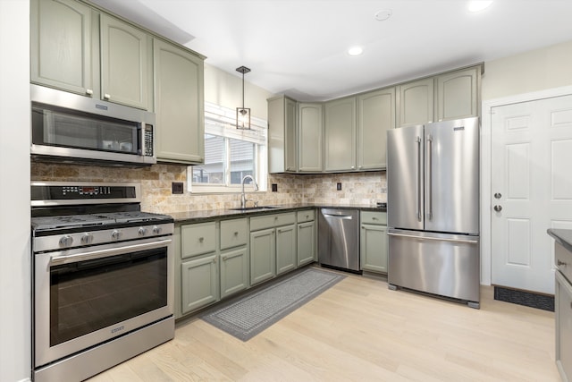 kitchen with pendant lighting, green cabinets, stainless steel appliances, and sink