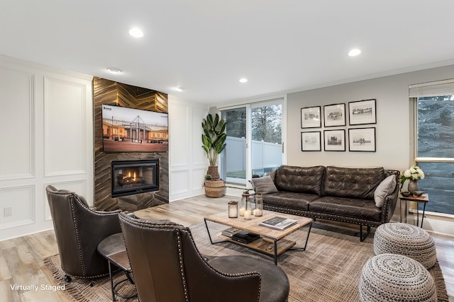 living room with crown molding, light hardwood / wood-style flooring, and a tile fireplace